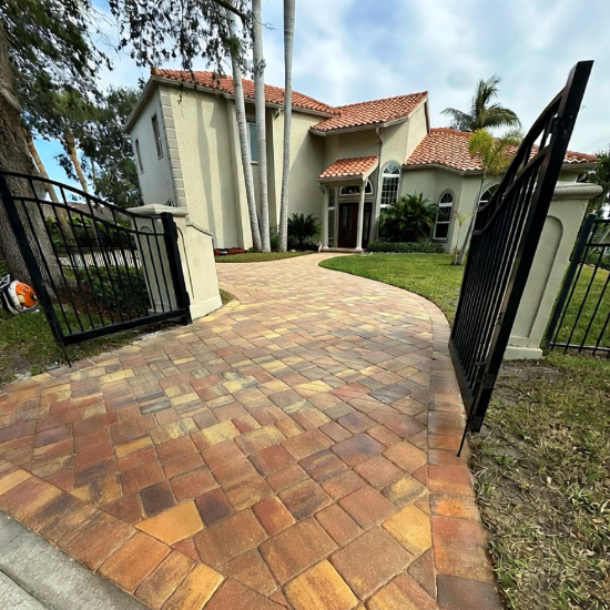 Paved driveway leading to a house with a black metal gate