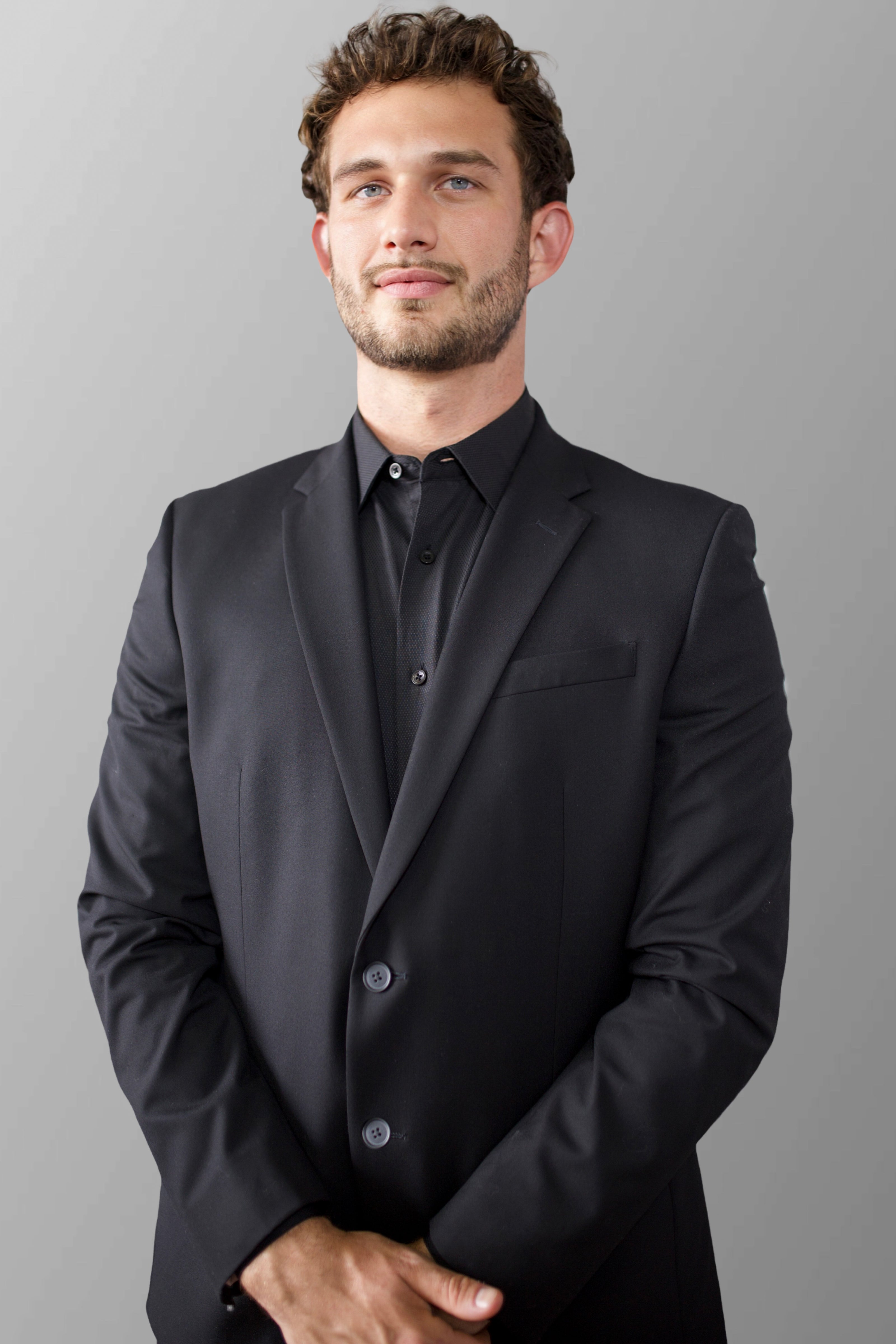 Dalton J Kelly wearing a black suit against a gray background